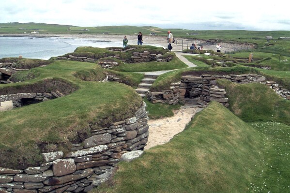 FILE - Visitors look at the 5,000 year-old remains of Skara Brae village in the Scottish Orkney Islands, July 19, 2005, which was revealed by a huge storm in 1850. Sick of being ignored by far-away politicians, officials on Scotland’s remote Orkney Islands are mulling a drastic solution. They want to rejoin Norway, the Scandinavian country that gave them away as a royal wedding dowry more than 550 years ago. Orkney Islands Council is due to debate options for “alternative models of governance” on Tuesday, July 4, 2023. ( AP Photo/Naomi Koppel, File)