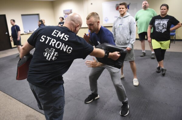 In this photo taken Sept. 10, 2019, Ryan Russo, second from left, goes through a drill with instructor Sean Fuller, left, during a defensive tactic training class at the American Medical Response training center in Clackamas, Ore. Paramedics in Portland are undergoing mandatory training in defensive tactics after a rash of high-profile attacks against them as they respond to 911 calls for people in a mental health or drug-related crisis. (AP Photo/Steve Dykes)