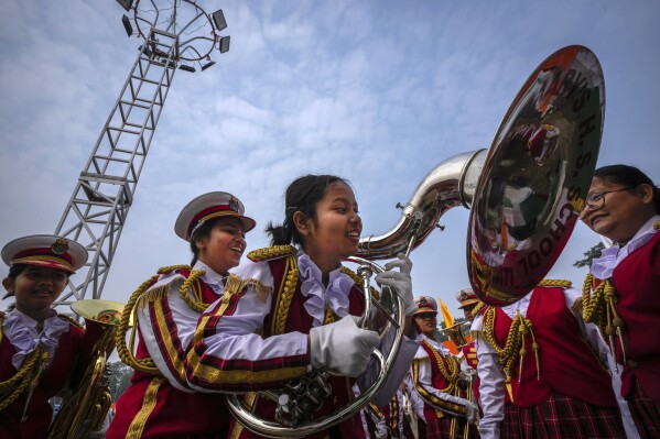 A school student helps another to hold a musical instrument before participate in the Republic Day parade in Guwahati, India, Friday, Jan. 26, 2024. (AP Photo/Anupam Nath)