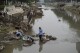 Residents wash their suitcase and belongings on a damaged bank of a canal clogged with flood debris in the aftermath of flood waters from an overflowing river in the Mentougou district on the outskirts of Beijing on Monday, Aug. 7, 2023. The death toll in recent flooding in China's capital rose, officials said Wednesday, as much of the country's north remains threatened by unusually heavy rainfall. (AP Photo/Andy Wong)