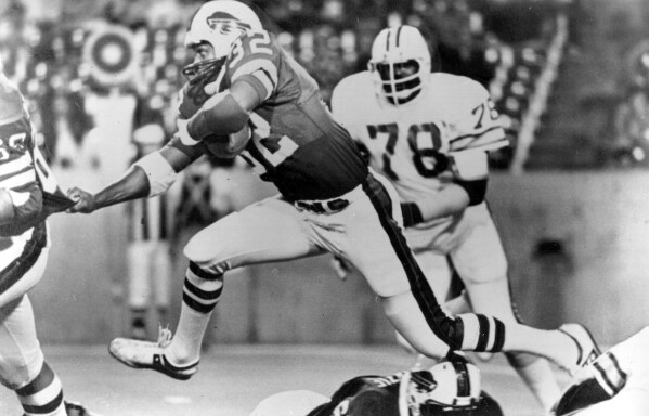 FILE - Buffalo Bills runningback O.J. Simpson (32) runs over some teammates as he latches onto Joe DeLamielleurs (68) during an NFL football game against the Tampa Bay Buccaneers at Rich Stadium in Buffalo, N.Y., Sept. 3, 1977. Buccaneers Council Rudolph (78) follows at right. (AP Photo/File)
