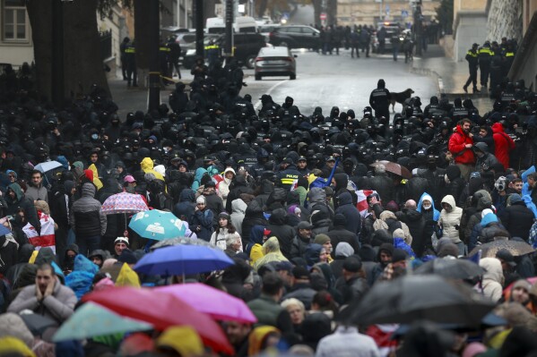 Police block protesters gathered in a street during a rally to demand new parliamentary elections in the country, near the Parliament's building in Tbilisi, Georgia, Monday, Nov. 25, 2024. (AP Photo/Zurab Tsertsvadze)