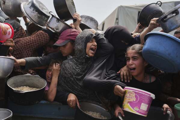 Palestinian children at a food distribution center in Khan Younis, Gaza Strip, Monday, April 21, 2025. (AP Photo/Abdel Kareem Hana, File)