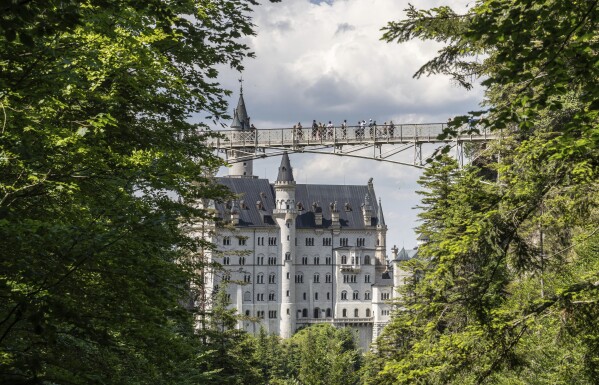 FILE - People stay on the Marien-Bridge at Castle Neuschwanstein, a 19th century creation by Bavaria's fairy tale king Ludwig II and world renowned tourist attraction, is pictured in Hohenschwangau near Fuessen, southern Germany, Thursday, June 15, 2023. A U.S. hiker who was sexually assaulted and killed in Germany last week had just graduated from the University of Illinois with a computer science degree in May. A Michigan man attacked her and a 22-year-old friend while they were hiking near Neuschwanstein castle on June 14. (Frank Rumpenhorst/dpa via AP, File)