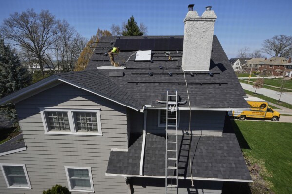 Theodore Tanczuk, of solar installer YellowLite, works to put panels on the roof of a home in Lakewood, Ohio, Wednesday, April 16, 2025. (AP Photo/Sue Ogrocki)
