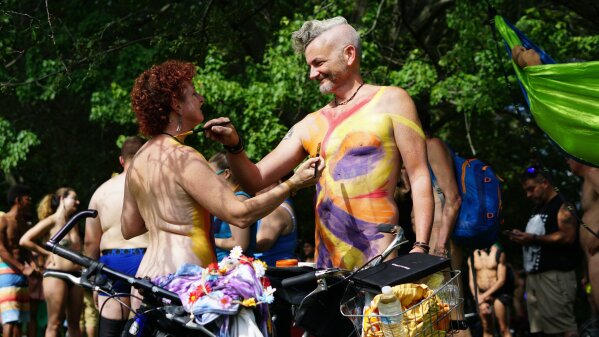 In this photo provided by David Cimetta, Melanie and Jim OâConnor paint each other's nude body while standing next to their bicycles before the start of the Philly Naked Bike Ride in Philadelphia on Saturday Aug. 24, 2019. (David Cimetta via AP)
