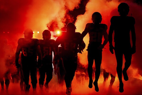 B.C. Lions players are silhouetted as they run onto the field for a Canadian Football League game against the Winnipeg Blue Bombers on Friday, Oct. 6, 2023, in Vancouver, British Columbia. (Darryl Dyck/The Canadian Press via AP)
