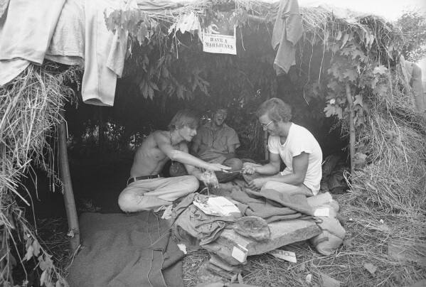 Music fans seek shelter in a grass hut at the Woodstock Music and Art Festival in Bethel, N.Y., Aug. 17, 1969. (AP Photo/File)