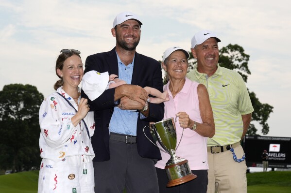 Scottie Scheffler, center, poses with his baby son Bennett and his wife Meredith, left, along with his parents Diane Scheffler, second from right, and Scott Scheffler, right, after winning the Travelers Championship golf tournament at TPC River Highlands, Sunday, June 23, 2024, in Cromwell, Conn. (AP Photo/Seth Wenig)