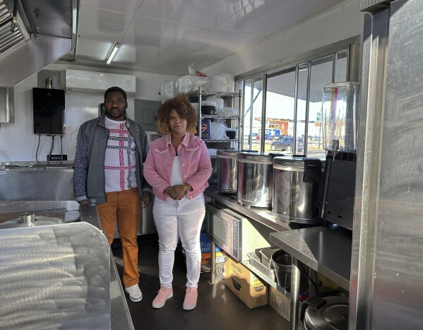 Theslet Benoir and Clemene Bastien stand inside their Eben-Ezer Haitian food truck in Parksley, Va., on Wednesday, Jan. 24, 2024. (AP Photo/Ben Finley)