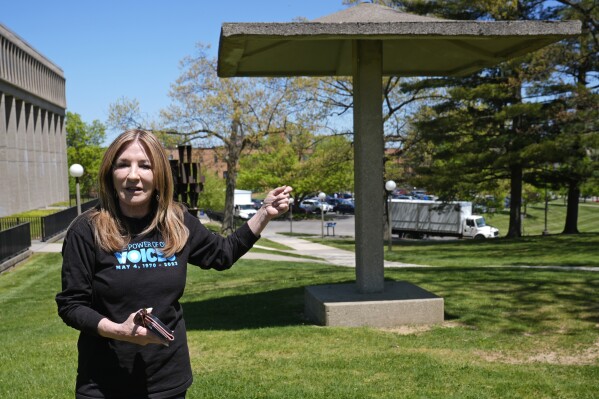 Chic Canfora recounts the events of May 4, 1970, standing at the pagoda where National Guardsmen knelt and shot towards students in the parking lot at rear, during an interview Thursday, May 2, 2024, in Kent, Ohio. (AP Photo/Sue Ogrocki, File)