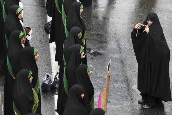 
              FILE - In this Nov. 25, 2011 file photo, female members of the Iranian paramilitary Basij force, affiliated with the Revolutionary Guard stand in formation as a woman photographs them in a rally in front of the former US Embassy in Tehran, Iran. On Monday, April 8, 2019, the Trump administration designated Iran’s Revolutionary Guard a “foreign terrorist organization” in an unprecedented move against a national armed force. Iran’s Revolutionary Guard Corps went from being a domestic security force with origins in the 1979 Islamic Revolution to a transnational fighting force.(AP Photo/Vahid Salemi, File)
            