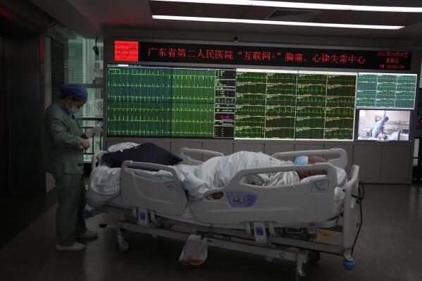 A patient moves past a display showing the real-time electrocardiograms of patients at the department of cardiovascular medicine of the Guangdong Second Provincial General Hospital in Guangzhou, in southern China's Guangdong province, Sunday, Sept. 26, 2021. The hospital in southern China's Guangdong Province is using 5G and IoT technologies to collect, transmit and monitor more data in real time, allowing healthcare workers to provide better medical service for patients. (AP Photo/Ng Han Guan)
