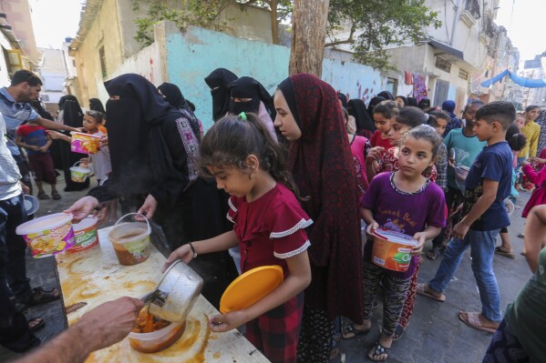 FILE - Palestinians receive food in Rafah, southern Gaza Strip, Wednesday, November 8, 2023. As the war between Israel and Hamas enters its second month and more than 10,000 people are killed In Gaza, trapped civilians struggle to survive without electricity or running water.  .  Every day became a mind-numbing cycle of searching for bread and water and waiting in line.  A sense of hopelessness is straining Gaza's close-knit society.  (AP Photo/Hatem Ali, file)