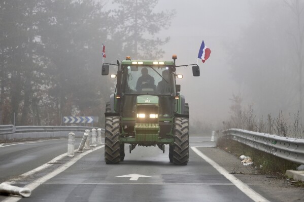 A farmer drives his tractor on a highway, near Agen, southwestern France, Saturday, Jan. 27, 2024. French farmers have vowed to continue protesting and are maintaining traffic barricades on some of the country's major roads. The government announced a series of measures Friday but the farmers say these do not fully address their demands. (AP Photo/Fred Scheiber)