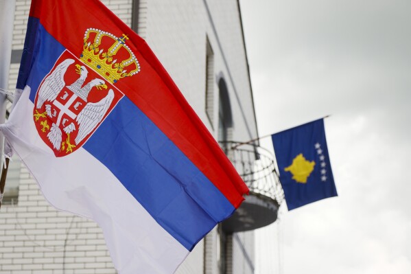 FILE - The Serbian flag, left, flies on a lamppost in front of a Kosovo flag on the city hall in the town of Zubin Potok, northern Kosovo, Wednesday, May 31, 2023. Kosovo’s government has postponed a deadline by two weeks for ethnic Serbs living in the country to register their vehicles with Kosovo license plates instead of Serbian ones. The move on Thursday, Nov. 30 was made to give ethnic Serbs more time to comply with the order. (AP Photo/Marjan Vucetic, file)