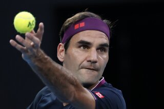 FILE - In this Jan. 30, 2020 file photo, Switzerland's Roger Federer serves to Serbia's Novak Djokovic during their semifinal match at the Australian Open tennis championship in Melbourne, Australia.  Federer’s agent tells The Associated Press, Sunday, Dec. 27,  that the 20-time Grand Slam champion is withdrawing from the Australian Open. Tony Godsick says Federer is still preparing to return to action after two operations on his right knee.  (AP Photo/Dita Alangkara, File)