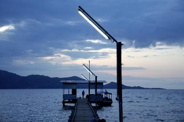 A man walks on a pier on Karampuang Island whose electricity relies on solar power plants, in West Sulawesi, Indonesia, Thursday, Dec. 22, 2022. While Indonesia has vast renewable and green energy potential from solar, wind, geothermal and other sources, experts warn that the vast archipelago nation faces unique financial, policy, infrastructure and other challenges that will require innovation.(AP Photo/Dita Alangkara)