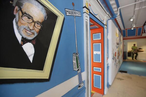 FILE — A mural that features Theodor Seuss Geisel, left, also known by his pen name Dr. Seuss, covers part of a wall near an entrance at The Amazing World of Dr. Seuss Museum, May 4, 2017, in Springfield, Mass. Sketches of fantastic creatures by Dr. Seuss that have never before been published will see the light of day in new books being written and illustrated by an inclusive group of up-and-coming authors and artists, the company that owns the intellectual property rights to Dr. Seuss' works announced Wednesday, March 2, 2022. (AP Photo/Steven Senne, File)