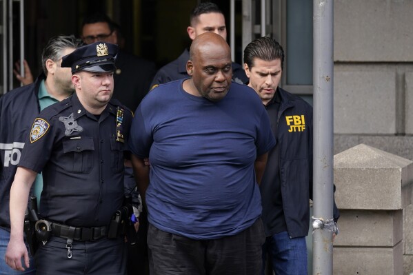 FILE - New York City police and law enforcement officials lead subway shooting suspect Frank James, center, away from a police station in New York on April 13, 2022. James, who sprayed the inside of a New York City subway train with gunfire and then slipped away in a stunned crowd, is set to be sentenced Thursday, Oct. 5, 2023, in the morning rush-hour attack. (AP Photo/Seth Wenig, File)