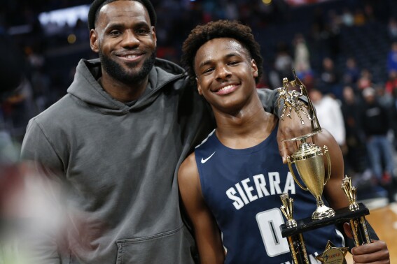 FILE - LeBron James, left, poses with his son Bronny after Sierra Canyon beat Akron St. Vincent - St. Mary in a high school basketball game, Saturday, Dec. 14, 2019, in Columbus, Ohio. LeBron James says his son, Bronny, is progressing in his rehabilitation from cardiac arrest in hopes of playing for the University of Southern California this season. James gave the update on his 18-year-old son Monday, Oct. 2, 2023, when the Los Angeles Lakers held their annual media day ahead of training camp. (AP Photo/Jay LaPrete, File)