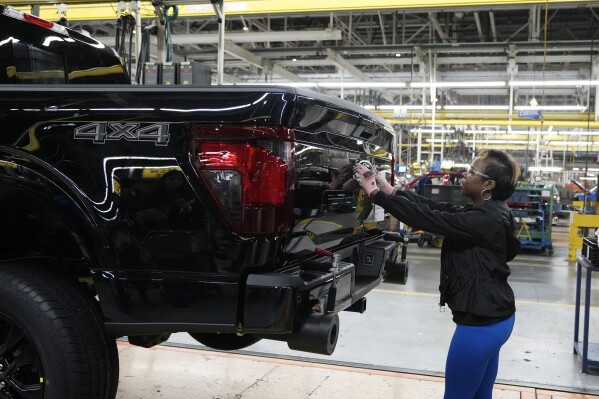 FILE - Assembly line worker Lashunta Harris applies the Ford logo on a 2024 Ford F-150 truck being assembled at the Dearborn Truck Plant, April 11, 2024, in Dearborn, Mich. On Friday, June 5, 2024, the U.S. government issues its June jobs report. (AP Photo/Carlos Osorio, File)