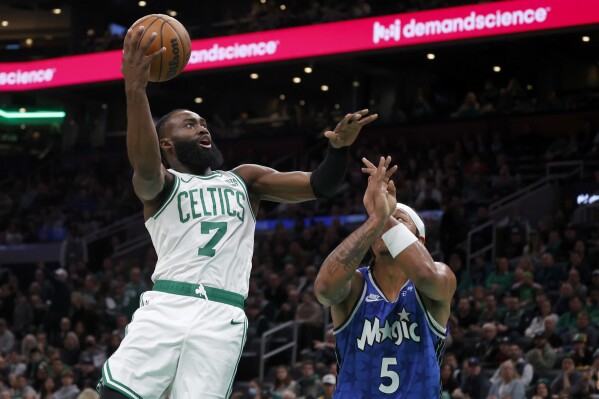 Boston Celtics guard Jaylen Brown (7) shoots over Orlando Magic forward Paolo Banchero (5) during the first half of an NBA basketball game, Sunday, Dec. 17, 2023, in Boston. (AP Photo/Mary Schwalm)