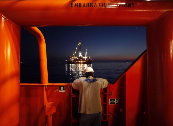 FILE - A crew member looks at the oil slick in the aftermath of the Deepwater Horizon oil rig collapse, Thursday, May 6, 2010 in the Gulf of Mexico. (AP Photo/Gerald Herbert)