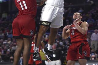 Wake Forest's Alondes Williams pulls back for a dunk between North Carolina State's Jaylon Gibson and Jericole Hellems during an NCAA college basketball game Wednesday, March 2, 2022 in Winston Salem, N.C. (Walt Unks/The Winston-Salem Journal via AP)