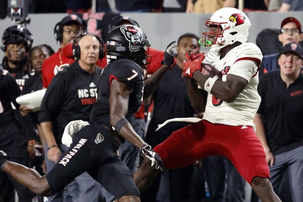 Louisville's Chris Bell catches the ball in front of North Carolina State's Shyheim Battle (7) during the second half of an NCAA college football game in Raleigh, N.C., Friday, Sept. 29, 2023. (AP Photo/Karl B DeBlaker)