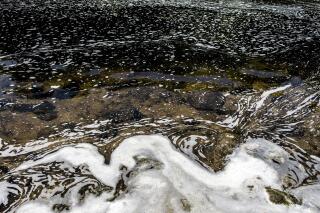 FILE - PFAS foam gathers at the the Van Etten Creek dam in Oscoda Township, Mich., near Wurtsmith Air Force Base on June 7, 2018. A Wisconsin judge is set to rule on whether the state Department of Natural Resources has the authority to regulate PFAS chemicals and other toxic compounds without established standards. (Jake May/The Flint Journal via AP, File)