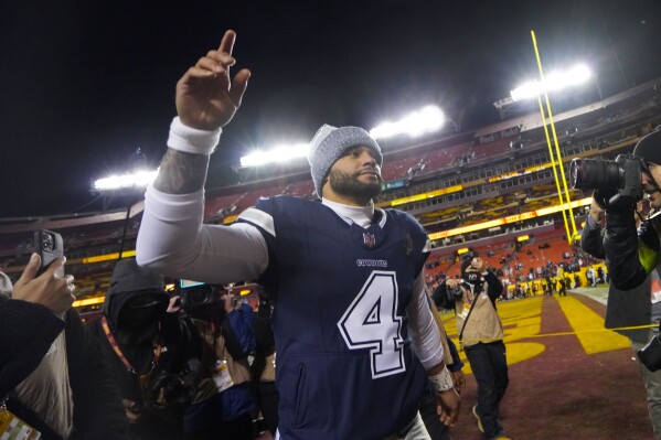 Dallas Cowboys quarterback Dak Prescott (4) raises his arm as he heads off the field after an NFL football game against the Washington Commanders, Sunday, Jan. 7, 2024, in Landover, Md. Dallas won 38-10. (AP Photo/Jessica Rapfogel)