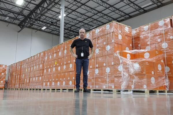 In this image provided by Direct Relief, Direct Relief CEO Thomas Tighe stands in front of boxes of N95 masks at Direct Relief’s Santa Barbara, Calif., warehouse and headquarters in March 2020. Since the war between Russia and Ukraine began in February, Tighe and the nonprofit humanitarian medical organization Direct Relief, where he has been president and CEO since 2000, have provided more than 50 million doses of medication and 254 tons of medical aid to those in Ukraine and neighboring countries. (Direct Relief via AP)
