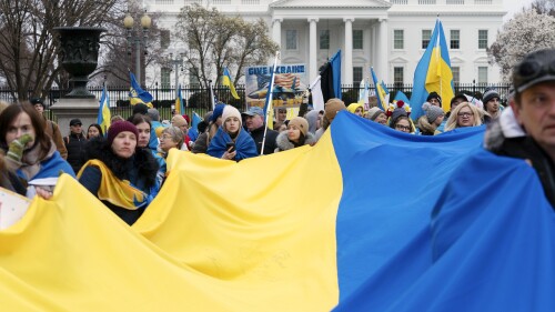 SÚBOR - Demonštranti s ukrajinskou vlajkou pochodujú pred Bielym domom na podporu Ukrajiny počas zhromaždenia vo Washingtone 25. februára 2023. Jeden z architektov tajnej americkej protisovietskej stratégie v Afganistane zverejnil nové monografie.  .  v 