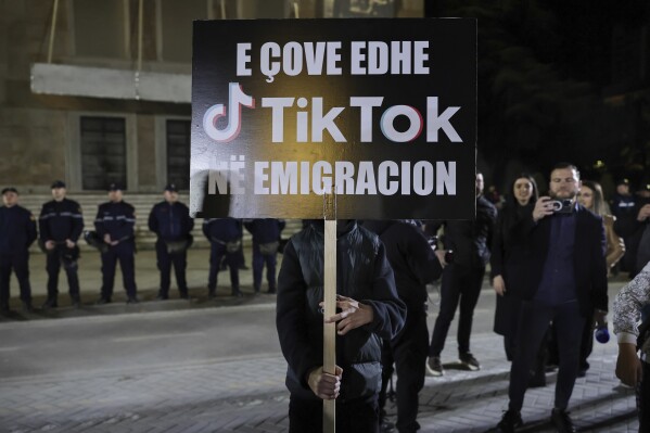 A protester holds a banner during a rally against the leftwing Socialist Party government's decision to shut down TikTok, in Tirana, Albania, Saturday, Mar. 15, 2025. The banner reads: " You immigrated TikTok too". (AP Photo/Vlasov Sulaj)