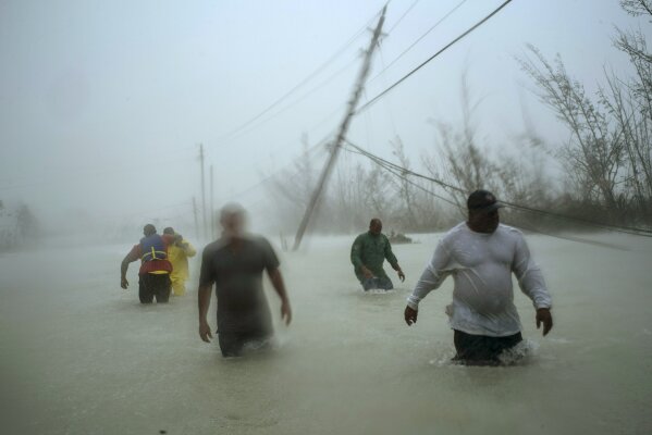 Volunteers walk under the wind and rain from Hurricane Dorian through a flooded road as they work to rescue families near the Causarina bridge in Freeport, Grand Bahama, Bahamas, Tuesday, Sept. 3, 2019. The storm’s punishing winds and muddy brown floodwaters devastated thousands of homes, crippled hospitals and trapped people in attics. (AP Photo/Ramon Espinosa)