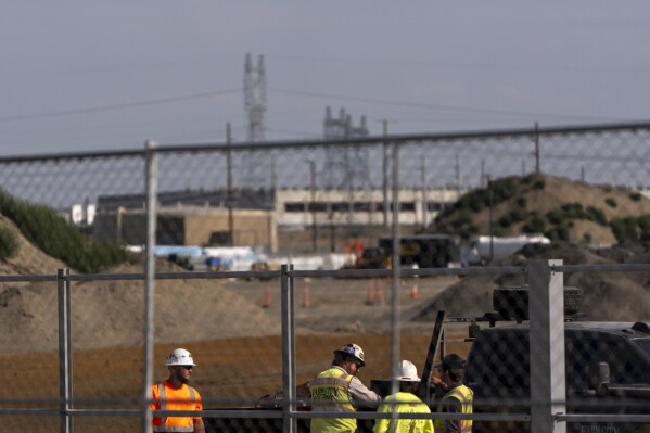 Workers talk outside an Amazon Web Services data center that is under construction on Wednesday, Aug. 21, 2024, in Boardman, Ore. (AP Photo/Jenny Kane)