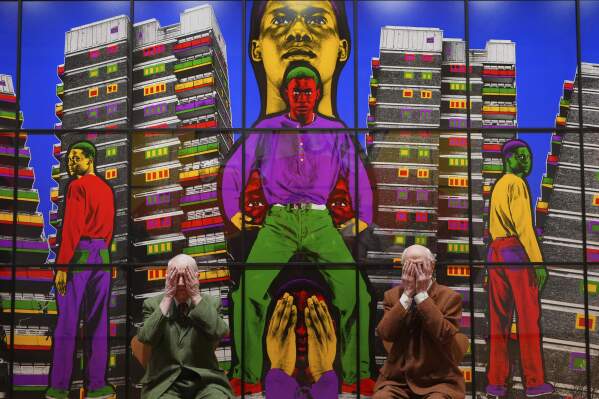 Artists Gilbert & George pose with artwork at their exhibition called 'DEATH HOPE LIFE FEAR…' an exhibition of 18 pictures by Gilbert & George that span the years 1984 to 1998, at the Gilbert & George Centre in London, Wednesday, May 14, 2025. (AP Photo/Kirsty Wigglesworth)