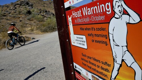 A cyclist finishes his ride early to beat high temperatures, Monday, July 10, 2023, in Phoenix. National Weather Service says Phoenix has had 10 consecutive days of 110 degrees or above. (AP Photo/Matt York)