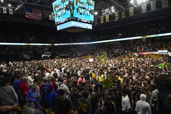 Central Florida fans storm the court after upsetting Kansas in an NCAA college basketball game, Wednesday, Jan. 10, 2024, in Orlando, Fla. (AP Photo/John Raoux)