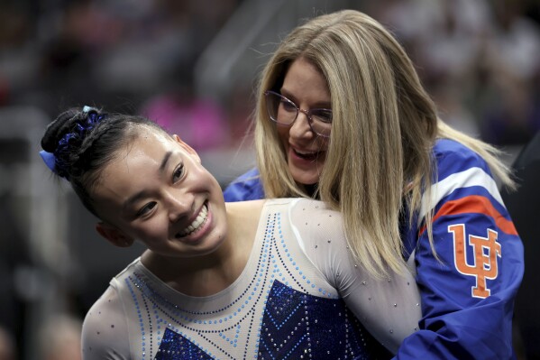 Leanne Wong, left, is congratulated by her coach Jenny Rowland, right, after competing in the floor exercise at the U.S. Gymnastics Championships, Friday, Aug. 25, 2023, in San Jose, Calif. (AP Photo/Jed Jacobsohn)