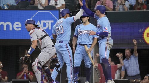 Texas Rangers' Ezequiel Duran (20) and Brad Miller, right, celebrate after scoring on Leody Taveras' double during the third inning of a baseball game against the Los Angeles Dodgers, Sunday, July 23, 2023, in Arlington, Texas. (AP Photo/Sam Hodde)