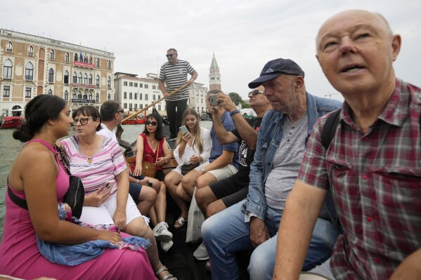 Tourists sit in a gondola during a short crossing of a canal, in Venice, Italy, Wednesday, Sept. 13, 2023. (AP Photo/Luca Bruno, File)