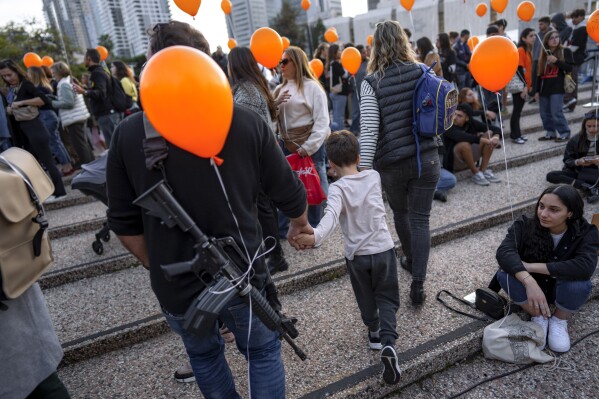 Demonstrators hold orange balloons at a rally in solidarity with Kfir Bibas, an Israeli boy who spent his first birthday Thursday in Hamas captivity in the Gaza Strip, in Tel Aviv, Israel, Thursday, Jan. 18, 2024. (AP Photo/Oded Balilty)