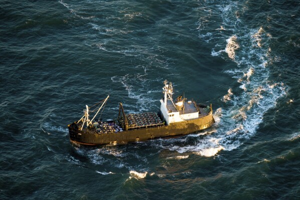 FILE - A crabbing vessel turns below a U.S. Coast Guard flyover inspection of crabbing ships along the Washington and Oregon coasts near Astoria, Ore., on Jan. 1, 2016. Oregon crab fishermen may soon face an indefinite extension of rules that for three seasons have restricted the number of pots allowed in the water to reduce the risk of whales and sea turtles getting entangled in fishing gear. (Joshua Bessex/The Astorian via AP, File)