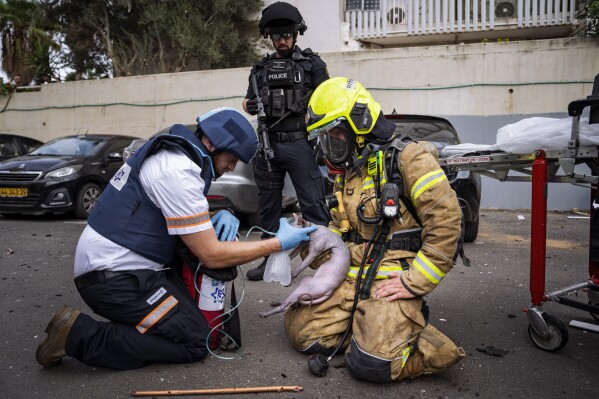 A firefighter and a paramedic deliver oxygen to an injured cat rescued from a building struck by a rocket fired from Gaza, in Tel Aviv, Israel, Friday, Oct. 27, 2023. (AP Photo/Oded Balilty)