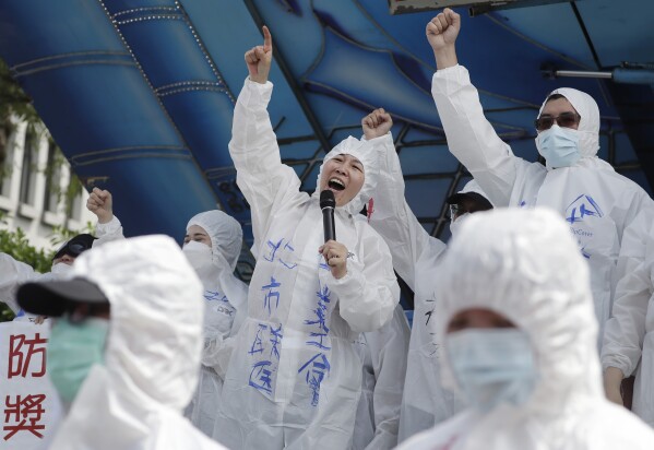 FILE - Medical personnel shout slogans as they protest on the street to ask for increasing labor welfare during a May Day rally in Taipei, Taiwan, Monday, May 1, 2023. The term 山道猴子 (shan dao hou zi), "mountain roadmonkey," became popular shorthand for young people's economic pressures in August, when a YouTube user dropped a 20-minute film called the "Life of a Mountain Roadmonkey." His story touched off a discussion about the low wages and long hours for many in Taiwan, where housing and traditional "success" are often out of reach. (AP Photo/Chiang Ying-ying)