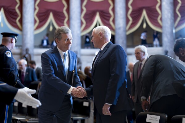 North Carolina Gov. Roy Cooper, left, greets former Vice President Mike Pence at a ceremony to unveil a bronzed sculpture of the late Rev. Billy Graham, at the U.S. Capitol in Washington, Thursday, May 16, 2024. Known as America's pastor, Graham died in 2018 at age 99. (AP Photo/J. Scott Applewhite)