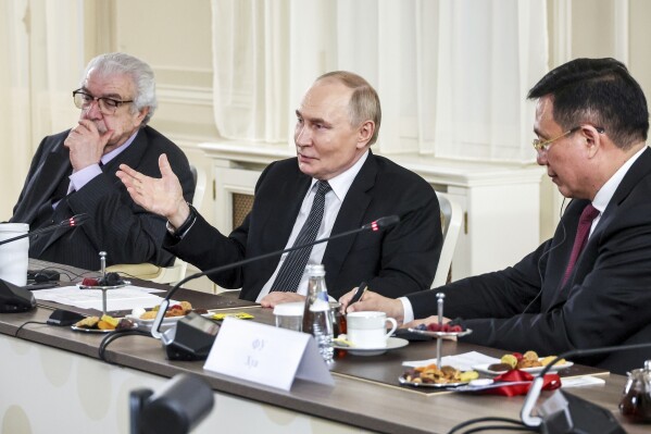 CORRECTS PHOTOGRAPHER'S NAME TASS news agency First Deputy Director General Mikhail Gusman, left, and Xinhua News Agency President Fu Hua, right, attend a meeting of Russian President Vladimir Putin, center, with the heads of international news agencies at the newly renovated St. Petersburg Rimsky-Korsakov State Conservatory on the sidelines of the St. Petersburg International Economic Forum in St. Petersburg, Russia, Thursday, June 19, 2025. (Alexander Demyanchuk, Sputnik, Kremlin Pool Photo via AP)