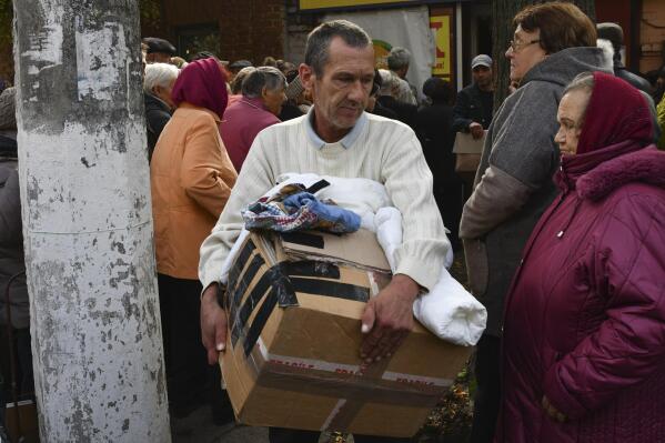 People receive humanitarian aid at a distribution point in Slavyansk, Donetsk region, Ukraine, Thursday, Oct. 6, 2022. (AP Photo/Andriy Andriyenko)